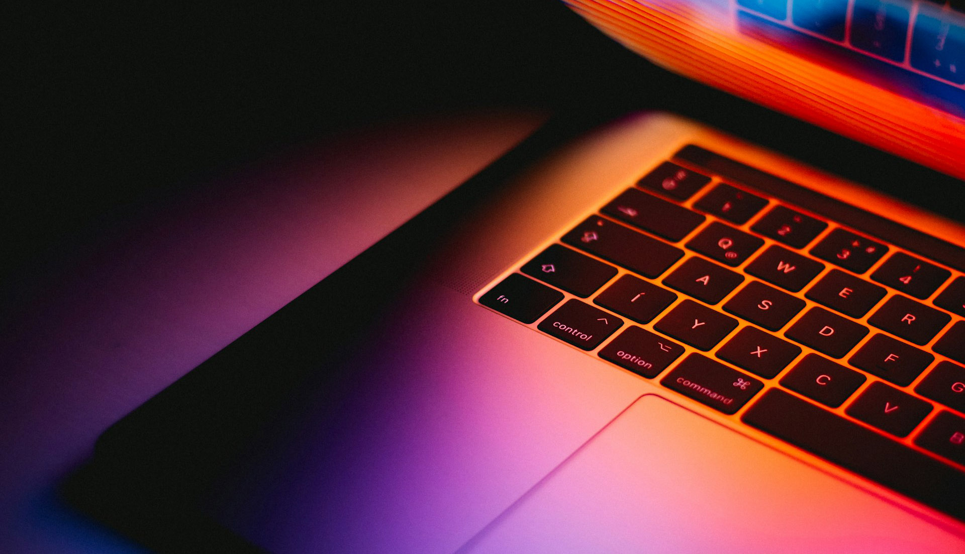 a dark image of a laptop keyboard with multicoloured lights