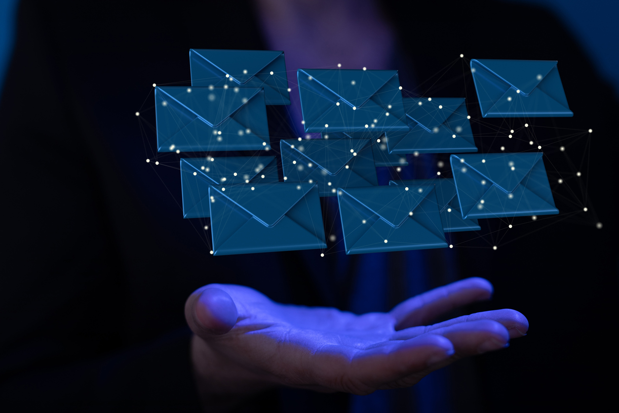 a hand on a dark background holding floating envelopes indicating emails