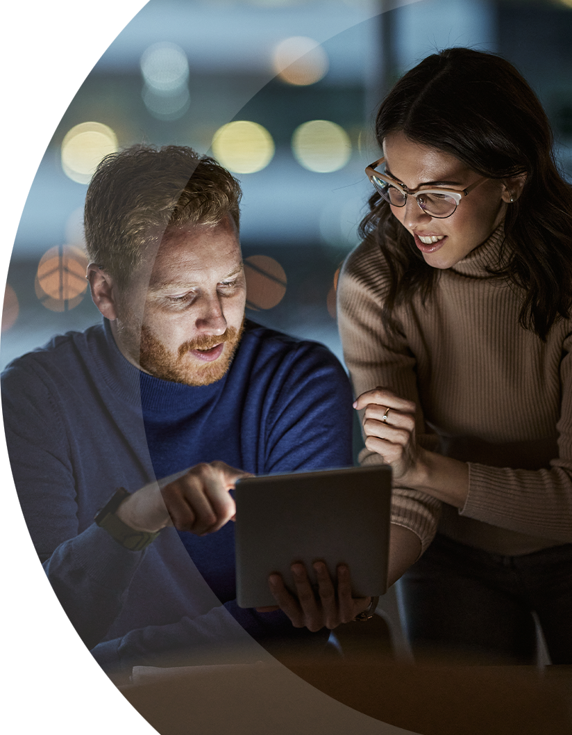 two IT employees looking at a tablet in the office at night